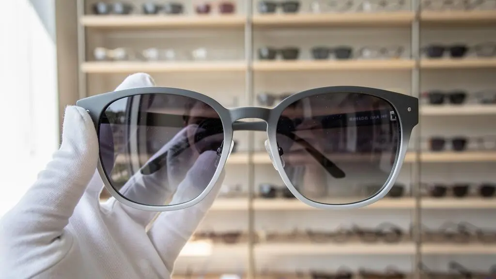 Des lunettes de soleil à monture grise dégradée tenues dans une boutique d'optique